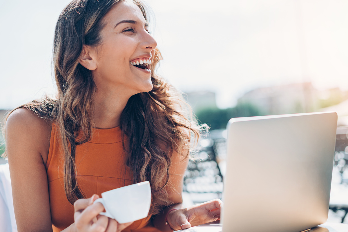 Happy woman with laptop and espresso